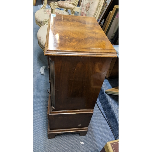 13 - A reproduction mahogany chest of drawers of small proportions having seven drawers and on bracket fe... 