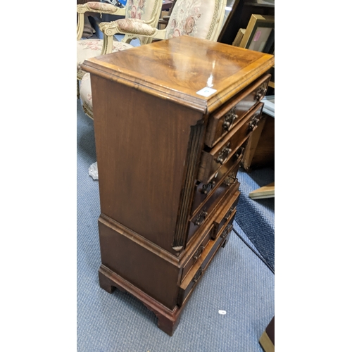 13 - A reproduction mahogany chest of drawers of small proportions having seven drawers and on bracket fe... 