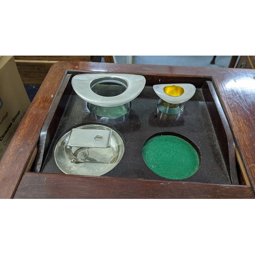 31 - A mid-20th century mahogany smoker's table, the top having a sliding fitted compartment and the cabr... 