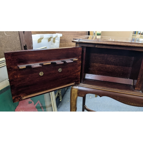 31 - A mid-20th century mahogany smoker's table, the top having a sliding fitted compartment and the cabr... 