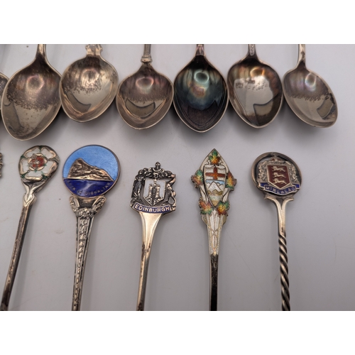 22 - A collection of silver and enamel souvenir spoons, decorated with enamel crest to the terminals to i... 