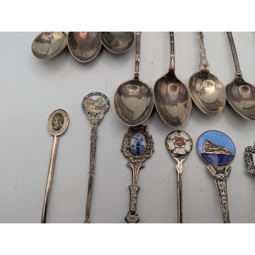 22 - A collection of silver and enamel souvenir spoons, decorated with enamel crest to the terminals to i... 