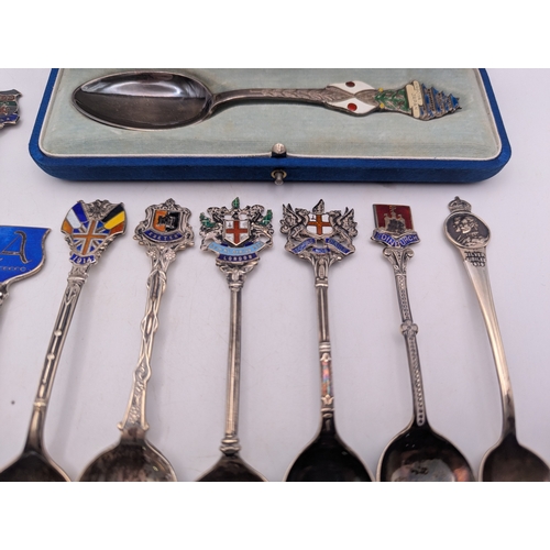 22 - A collection of silver and enamel souvenir spoons, decorated with enamel crest to the terminals to i... 