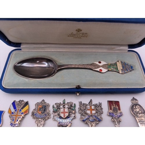 22 - A collection of silver and enamel souvenir spoons, decorated with enamel crest to the terminals to i... 