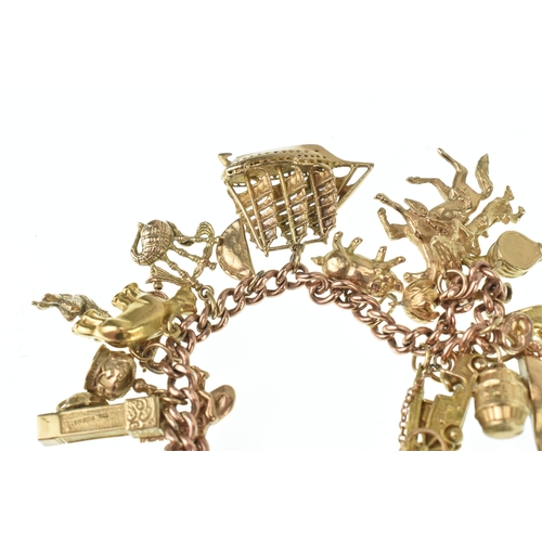 16 - A 9ct rose gold curb link charm bracelet, having a 9ct yellow gold, heart shaped padlock clasp and a... 