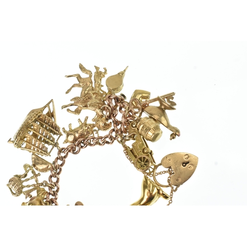 16 - A 9ct rose gold curb link charm bracelet, having a 9ct yellow gold, heart shaped padlock clasp and a... 