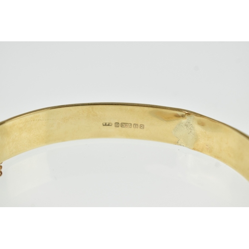 20 - A 9ct yellow gold hinged bangle having floral scroll engraved decoration to one half, box clasp A/F,... 