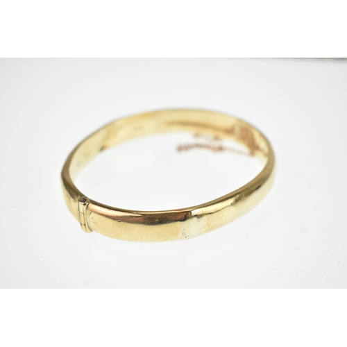 20 - A 9ct yellow gold hinged bangle having floral scroll engraved decoration to one half, box clasp A/F,... 