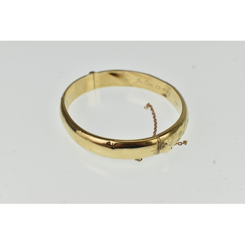 20 - A 9ct yellow gold hinged bangle having floral scroll engraved decoration to one half, box clasp A/F,... 