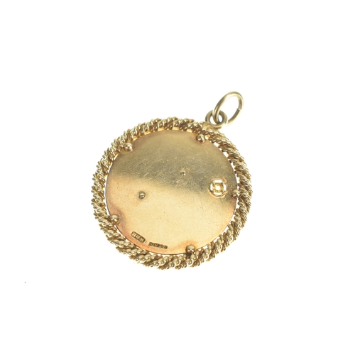 31 - A 9ct yellow gold pendant, featuring an engine turned ground, with inset pearl, decorated with two f... 