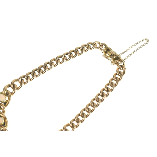 47 - A 15ct gold curb link bracelet, having graduating links interspersed with five oval opals in rubover... 