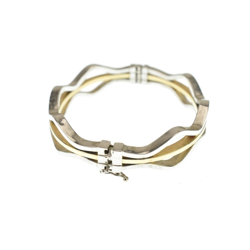 49 - A 14ct white and yellow gold bangle, having woven white gold bands enclosing a yellow gold band, con... 