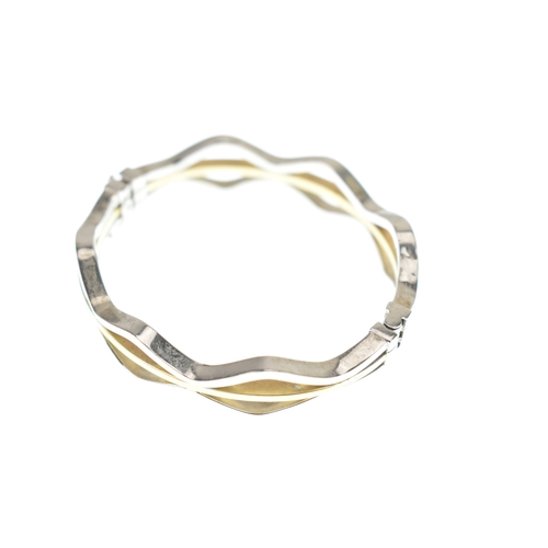 49 - A 14ct white and yellow gold bangle, having woven white gold bands enclosing a yellow gold band, con... 