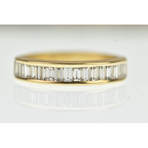 53 - A diamond yellow gold half eternity ring, unmarked, channel set with sixteen baguette cut diamonds, ... 