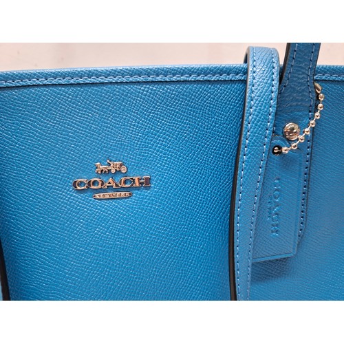 18 - Coach- An Azure blue crossgrain leather and coated canvas 'City Zip' tote bag having silver tone har... 