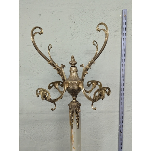 37 - A mid-20th century reproduction coat stand with onyx style column and ornate brass mounts on four sp... 