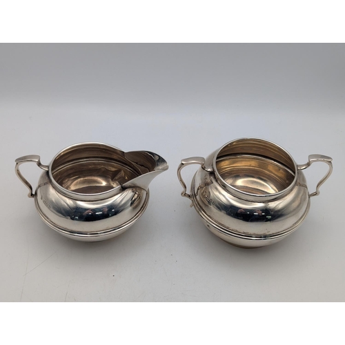 21 - A George V silver sugar bowl and cream jug, in bulbous form, hallmarked 1922, by Charles Boyton and ... 