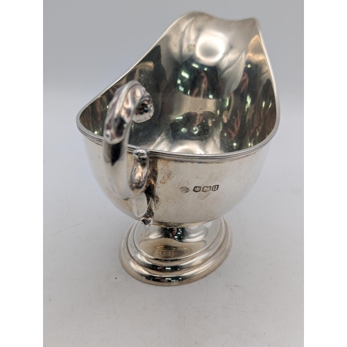 23 - A silver sauce boat with c-scroll handle and thumb rest, ribbed rim, on oval step foot, hallmarked S... 