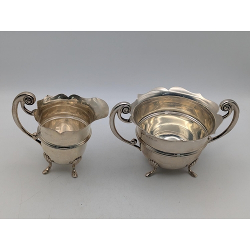 24 - Edwardian silver cream and sugar bowl having scalloped rims, c-scroll handles, on four feet, hallmar... 