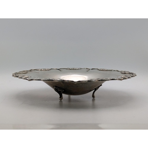 43 - An Egyptian silver dish with repeating bow shaped pierced border, 20cm diameter, on three feet, 248.... 