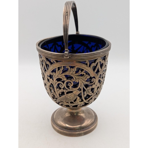 58 - A George V silver small pedestal basket with pierced c-scroll decoration and bird motifs, with blue ... 