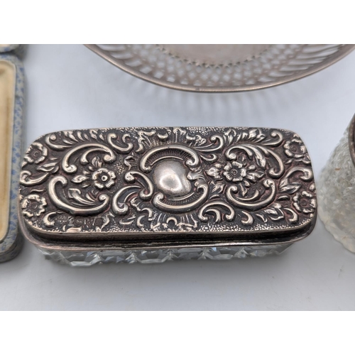 59 - A white metal dish having repeating pierced decoration, together with two silver topped dressing tab... 
