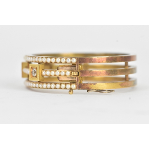 16 - A late Victorian seed pearl and diamond yellow gold hinged bangle, unmarked, of openwork triple-band... 