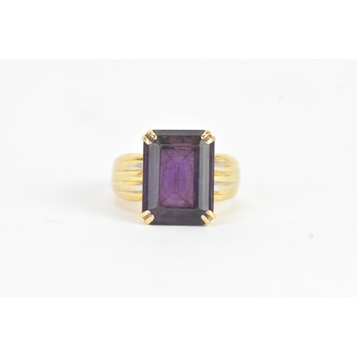 23 - An amethyst 18ct gold dress ring, the emerald cut amethyst in a four claw setting measuring approxim... 