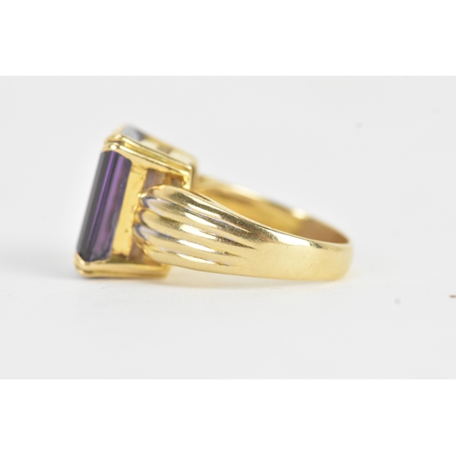 23 - An amethyst 18ct gold dress ring, the emerald cut amethyst in a four claw setting measuring approxim... 