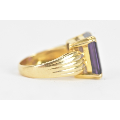 23 - An amethyst 18ct gold dress ring, the emerald cut amethyst in a four claw setting measuring approxim... 