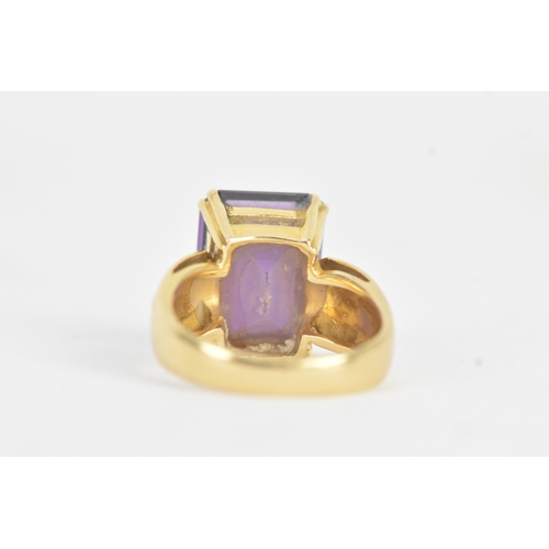 23 - An amethyst 18ct gold dress ring, the emerald cut amethyst in a four claw setting measuring approxim... 