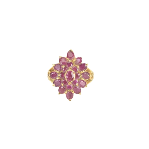 29 - A ruby 18ct yellow gold cluster dress ring, of radiating flower head design, set with twenty-one rub... 