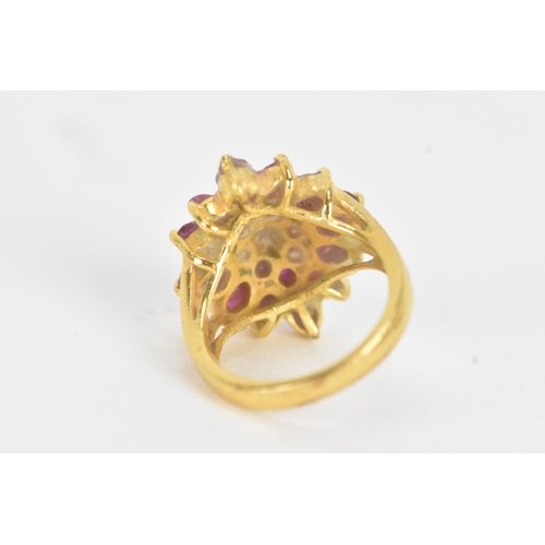 29 - A ruby 18ct yellow gold cluster dress ring, of radiating flower head design, set with twenty-one rub... 
