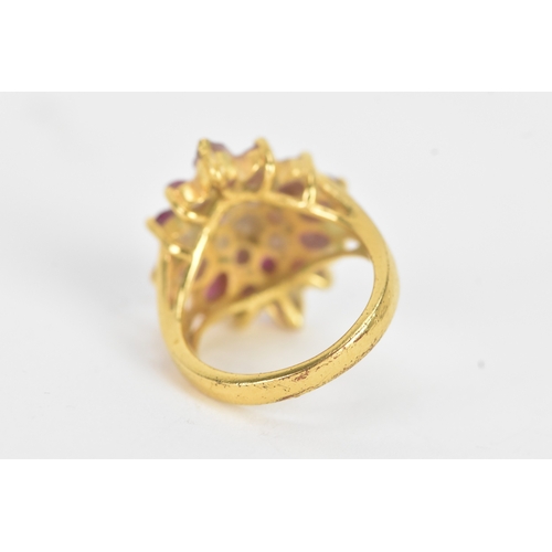 29 - A ruby 18ct yellow gold cluster dress ring, of radiating flower head design, set with twenty-one rub... 