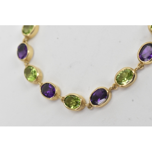 32 - A 9ct yellow gold bracelet featuring alternating oval-cut amethyst and peridots in a rub over settin... 