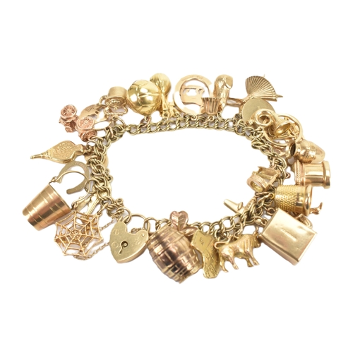 37 - A 9ct yellow gold double link charm link bracelet, having a heart shaped padlock clasp, having a lar... 