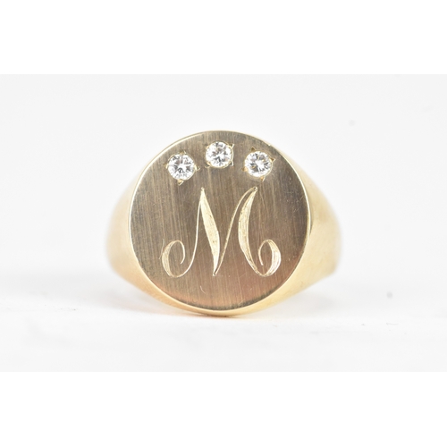 41 - A modern three stone diamond 10k yellow gold signet ring, engraved monogram letter 'M' and three ver... 