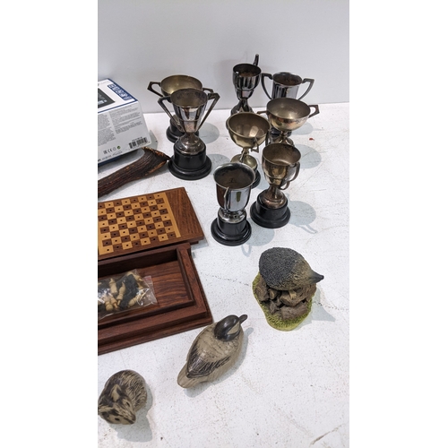 25 - A mixed lot to include silver plated trophies, Poole pottery ornaments, horn handled crumb scoop, lo... 