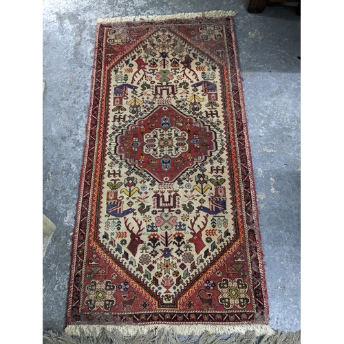 A group of three rugs to include a hand knotted Iranian rug with ...
