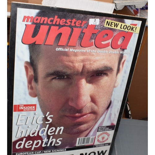 2 - A glass framed front cover of Eric Cantona featured on a Manchester United Club magazine 70cm's x 50... 