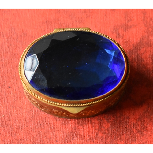 157 - Decorative gilt and blue glass oval trinket box. Good condition. Measures approx. 43mm x 33mm x 18mm