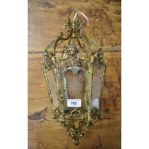 782 - A brass hanging lantern, decorated masks and other motifs, with cut glass panels, 24 cm wide