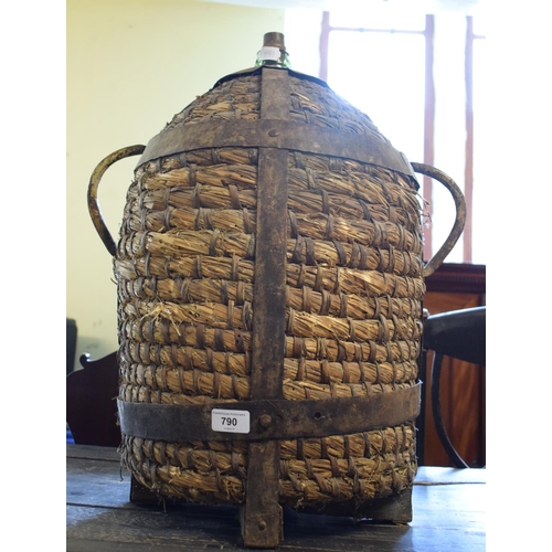 790 - A glass bottle, bound in rattan and with iron mounts, 56 cm high