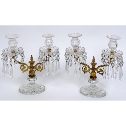 561 - A pair of Regency style gilt metal and cut glass two light candelabra, with prismatic drops, one sco... 