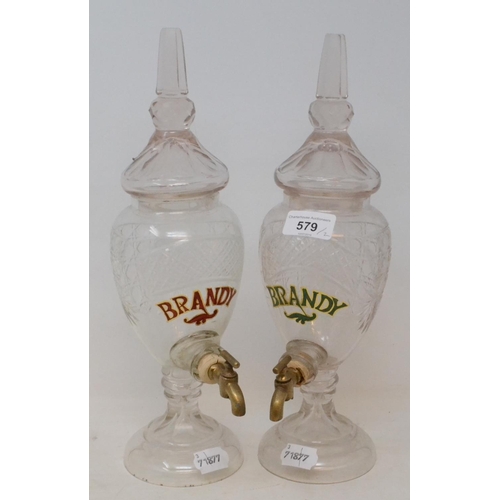 579 - A glass Brandy dispenser and cover, 34 cm high, and another matching (2)