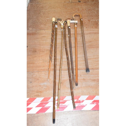 677 - A walking stick, with a turned ivory handle, other walking sticks and items (8)