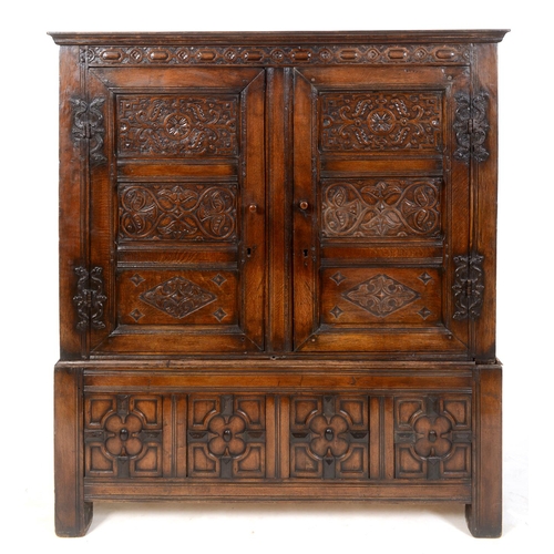 862 - An oak cupboard on stand, carved flowers and foliage, having a pair of panel doors, the base with fo... 