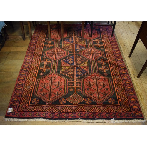 903 - An Eastern rug, decorated geometric motifs on a red ground, within a multi border, 151 x 200 cm