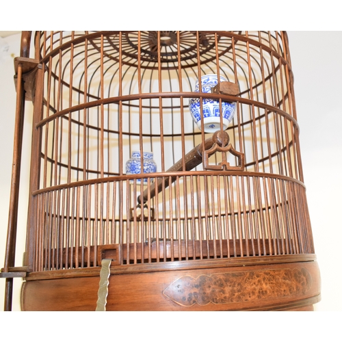 687 - A bird cage, fitted two porcelain feeders, 67.5 cm high, two table lamps, an embroidered panel, cric... 