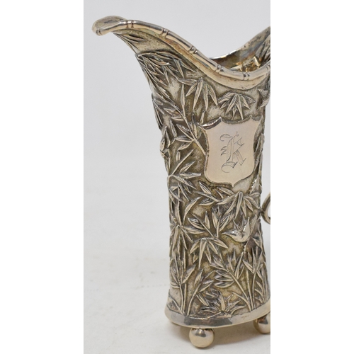 763 - An early 20th century Chinese export silver coloured metal cream jug, initialled, embossed bamboo an... 